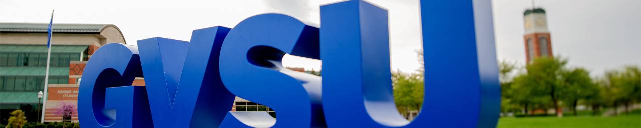 the large blue GVSU letters on the Allendale campus with the carillon tower in the background